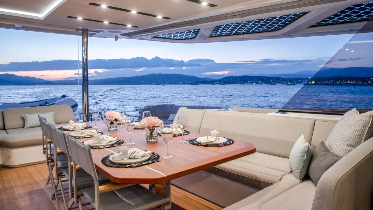 Aft cockpit dining area of the Fountaine Pajot Thira 80 catamaran with seating, a set table and open sea views